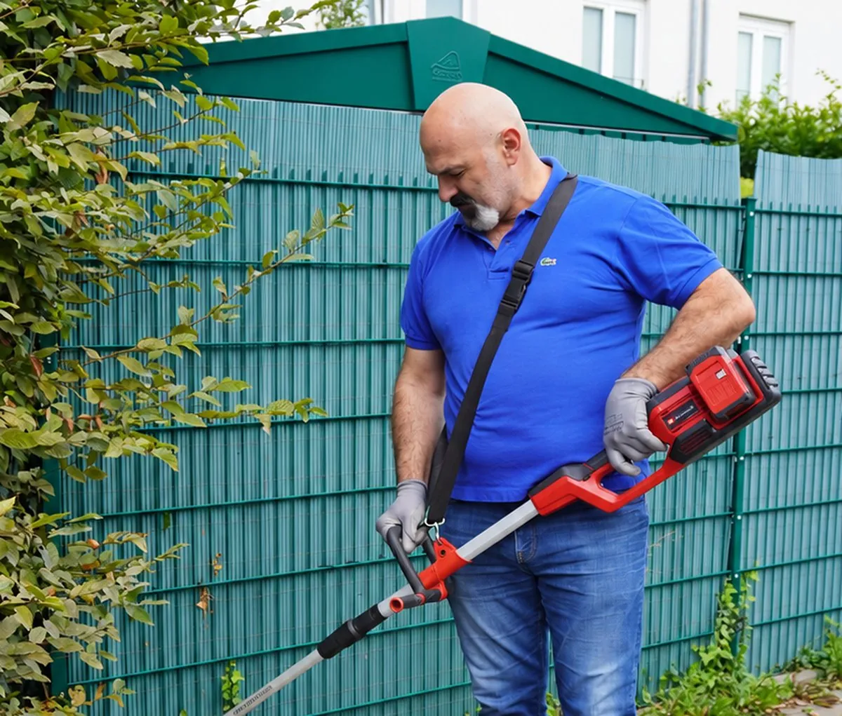 Zafer Sen schneidet mit dem Freischneider den Rand an einer Wohnanlage in Köln
